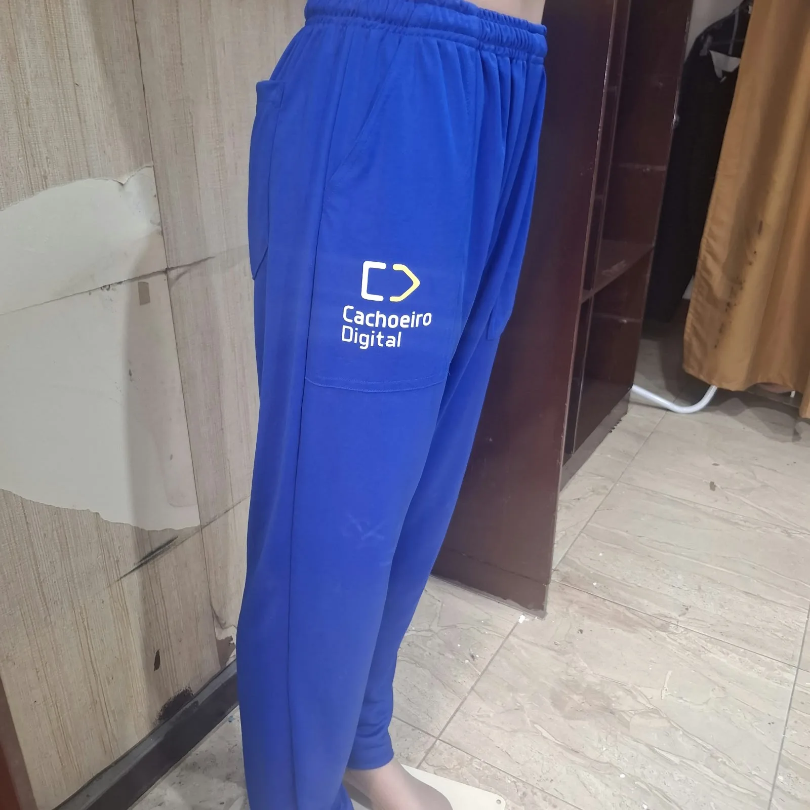 Pessoa vestindo calça jogger azul com bolso na lateral e logotipo Cachoeiro Digital na coxa.