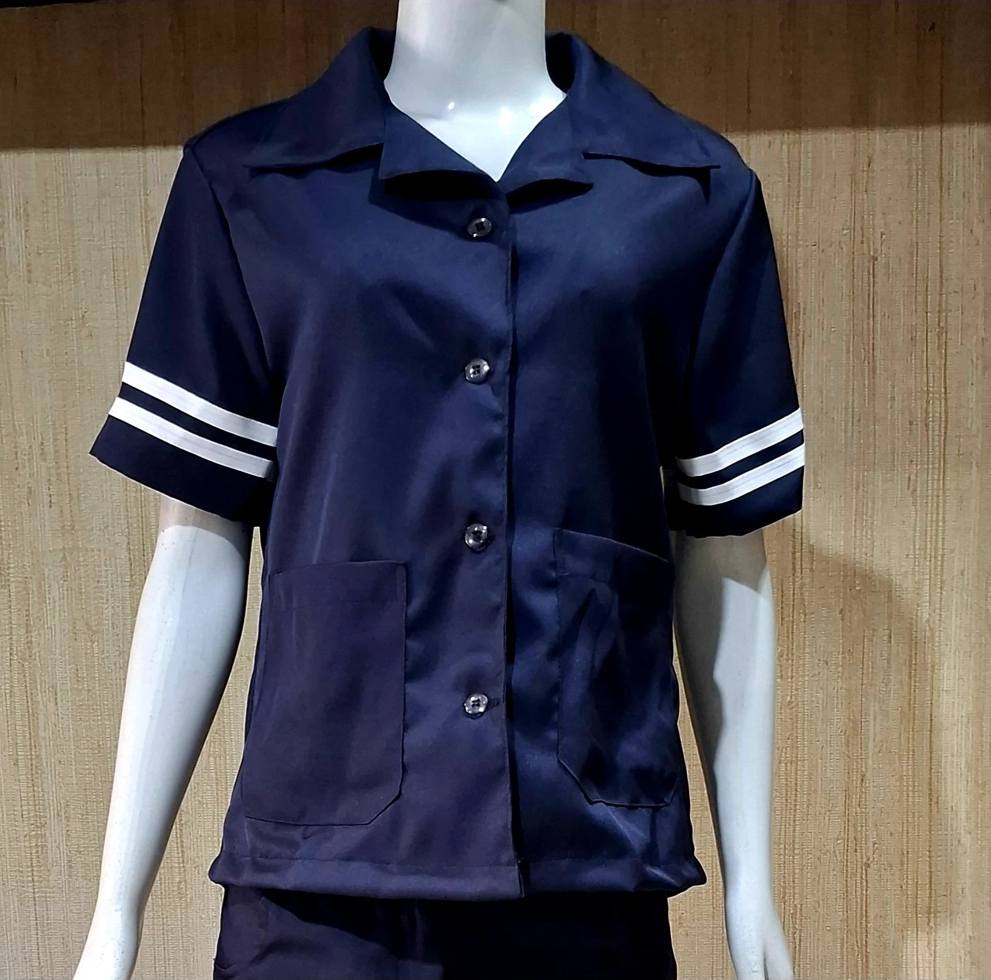 Manequim com camisa azul-marinho de manga curta, listras brancas na barra das mangas e dois bolsos frontais.