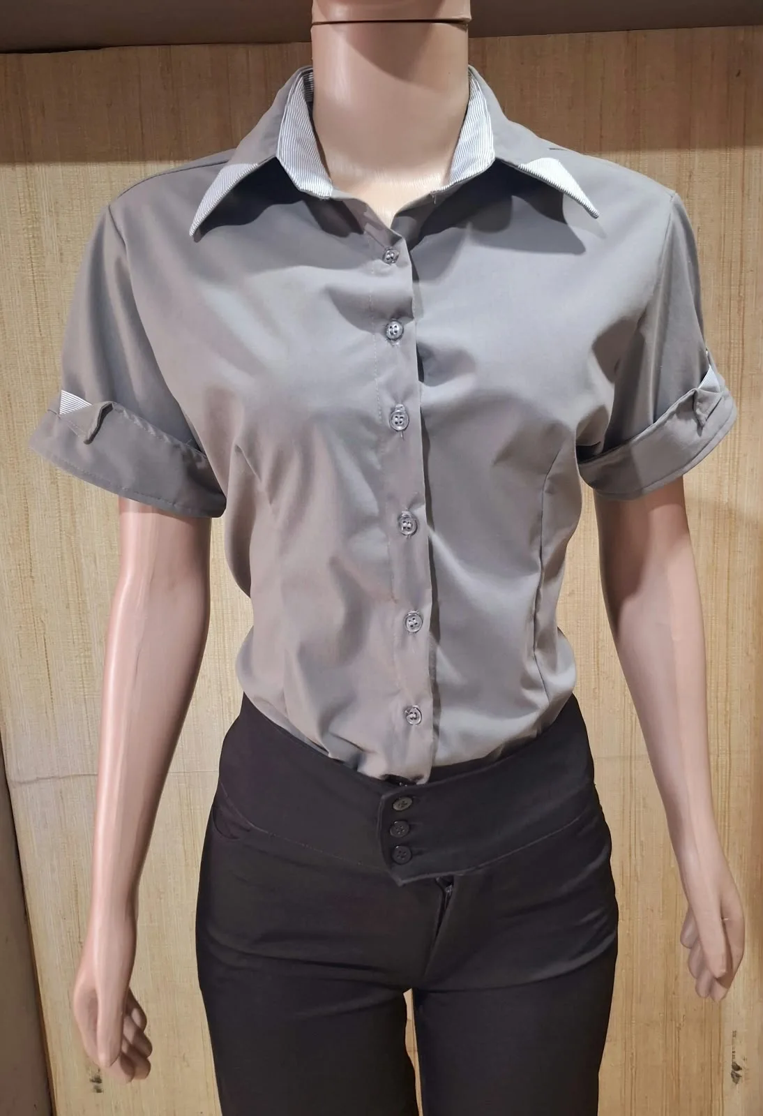 Manequim com camisa cinza de manga curta, gola com detalhe em listras e punhos dobráveis.